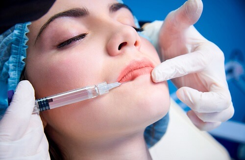 Beautiful young woman gets injection in lips. Beauty injections and cosmetology. Plastic and aesthetic surgery.